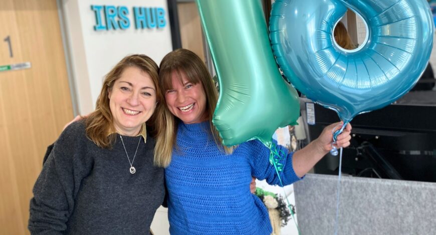 Kate Phillips and Natalie Pribil in the office with balloons to celebrate Natalie Pribil's 18 year anniversary at IRS